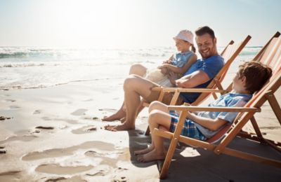 Father and kids sitting in chairs relaxing while watching the ocean waves