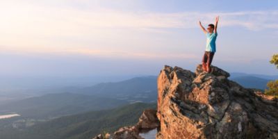 Man with hands up on top of cliff in Shenandoah National Park