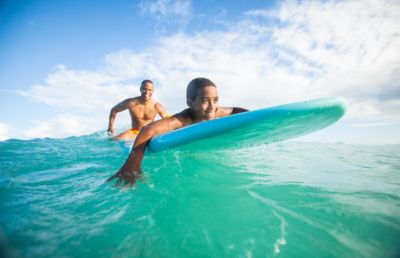 Father and sun body boarding in crystal clear ocean water