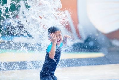 boy having fun with pool fountain waterpark