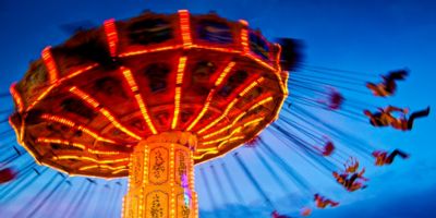 People swinging on merry-go-round swing set at Chairoplane during sunset