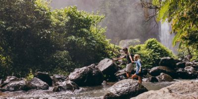 couple crossing stream on hike in Mountain Waters Scenic Byway