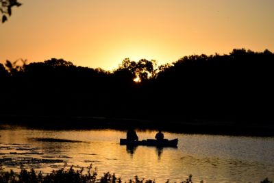 couple fishing on boat during sunset