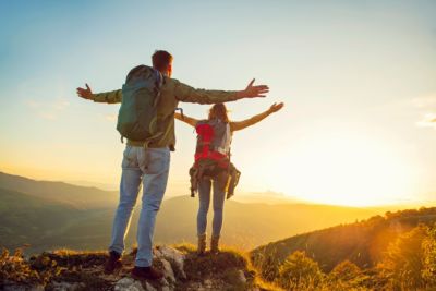 Couple hiking with back packs mountain view sunset