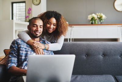couple sitting together on sofa using laptop