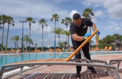 employee cleaning chairs by-pool