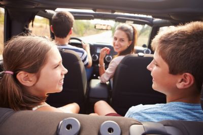 family in car boy and girl talking in back seat