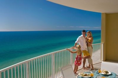 family of three standing on balcony overlooking ocean