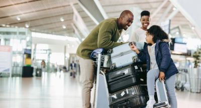 family with luggage trolley at airport