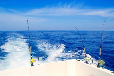 fishing boat trolling in deep blue sea rods reels