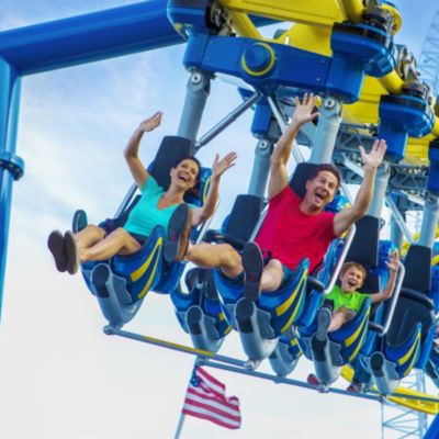 Family on roller coaster with hands up in the air