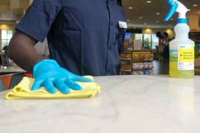 person cleaning counter with spray bottle
