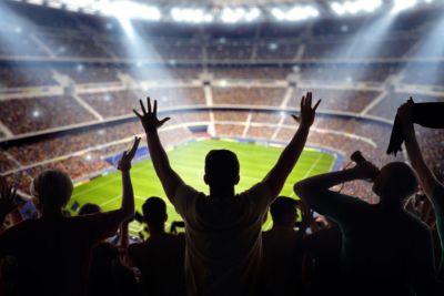 soccer fans at stadium cheering arms up