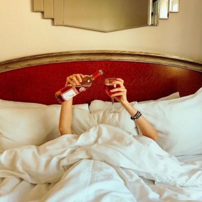 social ugc tori baker holding wine bottle glass in bed