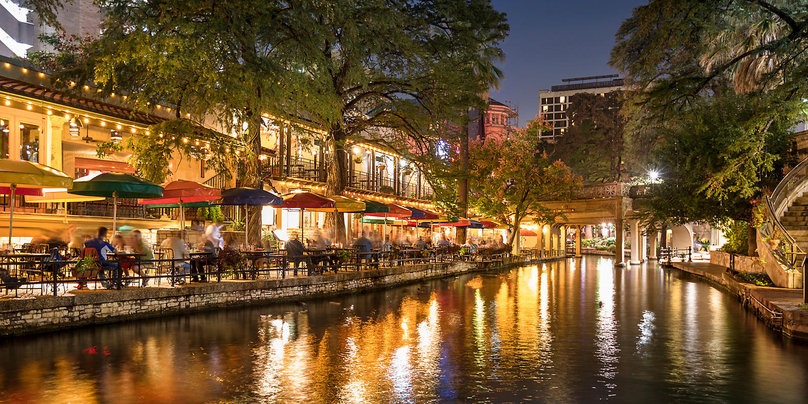 people dining at River Walk along the river at night