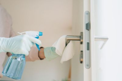 woman cleaning a door handle disinfection spray